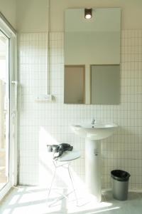 a white tiled bathroom with a sink and a chair at Samyan Story Boutique Hotel in Bangkok +77 photos