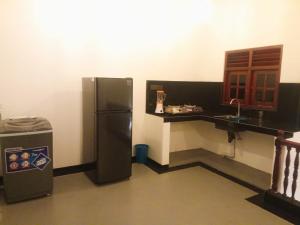 a kitchen with a refrigerator and a sink and a counter at Tranquil Cottage in Ahangama