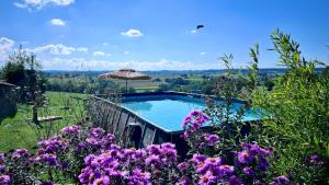 a swimming pool in a garden with purple flowers at Les Fresses Glamping in Saint-Julien-la-Genète