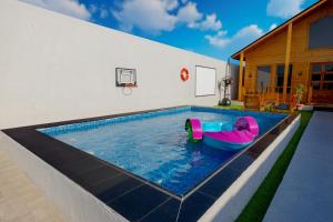 a swimming pool with a pink and blue raft in a house at أكواخ الردسي in Jeddah