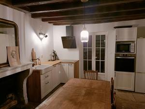 a kitchen with white cabinets and a wooden floor at La Petite Ecluse in Tanlay