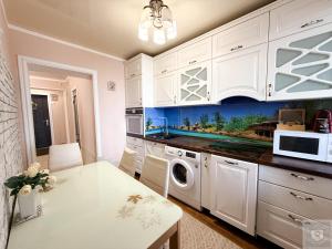 a kitchen with white cabinets and a washer and dryer at RentHouse Apartments Harmony in Chişinău