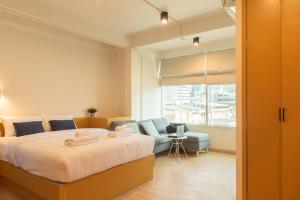 a bedroom with a bed and a couch and a window at Samyan Story Boutique Hotel in Bangkok