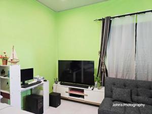 a living room with a large television and a couch at Iruka Guesthouse in Bandara