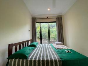 a bedroom with a bed with green pillows and a window at Golden Riverside Resort Kosgama in Kosgama