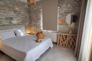 a bedroom with a white bed and a brick wall at Akallis Villa in Galini