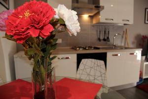 a vase with red and white flowers on a table at Katana Apartments in Catania