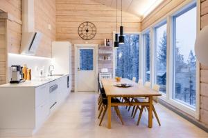Una cocina y un comedor con mesa y sillas de madera. en Villa Välke - Relax In Style, en Pyhätunturi