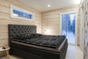 1 dormitorio con cama negra en una pared de madera en Villa Välke - Relax In Style, en Pyhätunturi