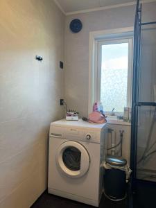 a washing machine in a bathroom with a window at Arctic Haven Apartment in Berlevåg