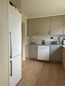 an empty kitchen with white cabinets and a refrigerator at Arctic Haven Apartment in Berlevåg