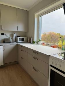 a kitchen with white cabinets and a large window at Arctic Haven Apartment in Berlevåg
