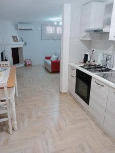 a kitchen with white cabinets and a wooden floor at L'alloggio delle vacanze estive in Corsano