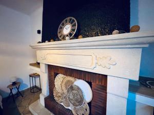 una chimenea con un reloj encima en Chez Mamie Wifi Un Séjour à Part, en Moyeuvre-Grande