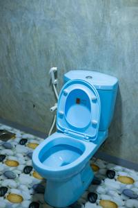 a blue toilet with the seat up in a bathroom at Dhanaya Safari Home in Udawalawe +42 photos