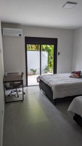 a bedroom with a bed and a desk and a window at 50m praia Cond pé na areia Alto padrao 4 suites Segur 24h Costa do sol Guaratuba Bertioga prox Riviera in Bertioga +29 photos