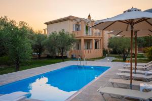 a villa with a swimming pool with chairs and an umbrella at Villa Agrilida in Vasiliki