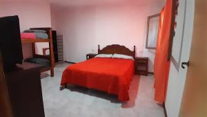 een slaapkamer met een rood bed en een rode deken bij La casita de Sanber in San Bernardo