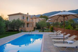 a pool with chairs and an umbrella and a house at Villa Agrilida in Vasiliki