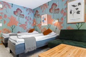two beds in a room with a couch and a table at Hotel Kuusamon Portti in Kuusamo