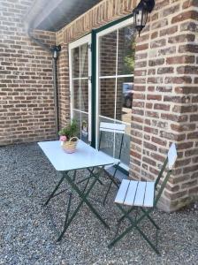 a picnic table and two chairs in front of a brick building at La Tanière du Lac in Robertville