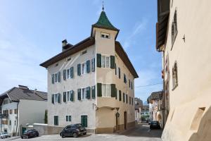 a tall building with a clock tower on a street at Villa Donata - Luxuriöses & großzügiges Apartment im Herzen von Kaltern, mit Innenhof, kostenlosem Parkplatz direkt am Haus in Caldaro