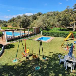 een achtertuin met een zwembad met schommels en een tafel bij Casa Palmeria , Quinta da Saudade in Armação de Pêra