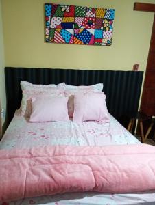a bed with a pink comforter and pillows at Regis pensão in Praia Grande