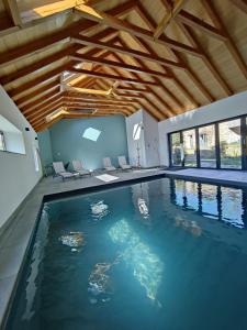 una piscina en una casa con techo de madera en Gîte avec piscine intérieure, en Moyrazès