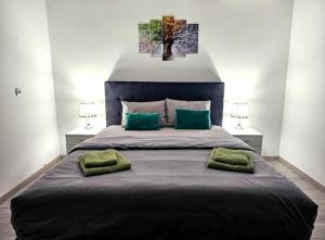 a bedroom with a large bed with two green pillows at SLEEP & GO in Surčin