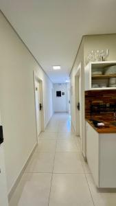Un pasillo con paredes blancas y un largo suelo blanco. en Nô Centro Suítes 2 - Apto moderno com cozinha compartilhada, en Florianópolis 19 fotos más