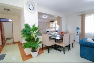 a dining room and living room with a table and a plant at Thome Urban Apartment in Ruringʼu +6 photos