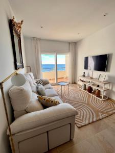 a living room with a white couch and a television at Sinfonía Azul vistas al mar in Estepona