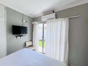 a bedroom with a bed and a tv and a window at Oteng Lifestyle BnB in Rustenburg