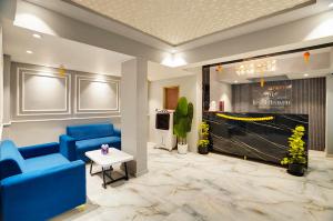 a lobby with blue chairs and a table and a tv at Hotel Regal Heaven in Pune