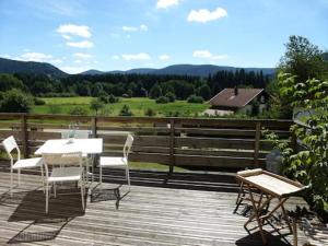 a patio with a table and chairs on a wooden deck at AB Bel appartement 1 à 4 pers face vallée 3 étoiles WIFI in Le Tholy