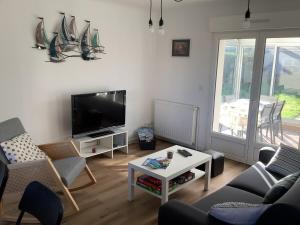 Il comprend un salon doté d'une télévision, de chaises et d'une table. dans l'établissement Gite Ty ar vor classé 3 étoiles, à Paimpol