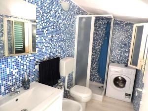 a blue tiled bathroom with a washer and dryer at Casa vacanze da Giovanni in Marina di Ragusa