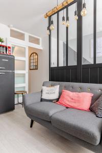 a gray couch with two pillows on it in a living room at Escale à Clisson - L'atelier in Clisson