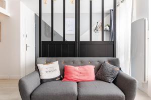 a gray couch with two pillows on it in a room at Escale à Clisson - L'atelier in Clisson
