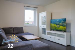 a living room with a couch and a flat screen tv at Sünnenhuus 32 - Dein Ferienhaus an der Thülsfelder Talsperre in Garrel