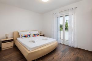 a white bedroom with a large bed and a window at Villa Laura Apartments in Zečevo Rogozničko
