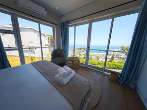 a bedroom with a bed with a view of the ocean at African Sunsets Camps Bay in Cape Town +28 photos
