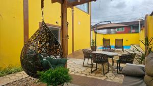 a yellow building with a patio with a table and chairs at Pousada Bella Juquehy in Juquei