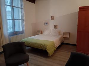 a bedroom with a bed and a chair and a window at Studio de charme in Castelnaudary