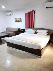 a large bed in a room with a couch at Taverna Lounge & Boutique Hotel in Port Harcourt