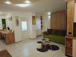 a living room with a green couch and a table at RA Studio Băile Olănești in Livadia