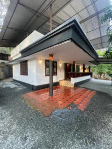 a small white building with a black roof at Rock Hill - Pachakkad Home Stay in Athirappally