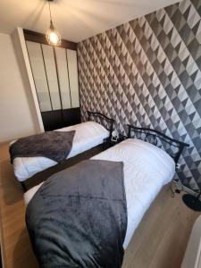 a bedroom with two beds and a wall at Le chou marin, charmante maison de plain-pied proche d'Audresselles & du Cap gris nez in Audinghen +9 photos
