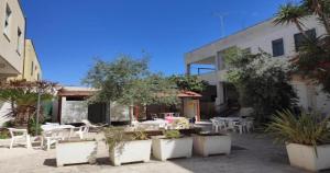 a courtyard with tables and chairs and a building at Odegos Residence Torre dell'Orso in Torre dell'Orso